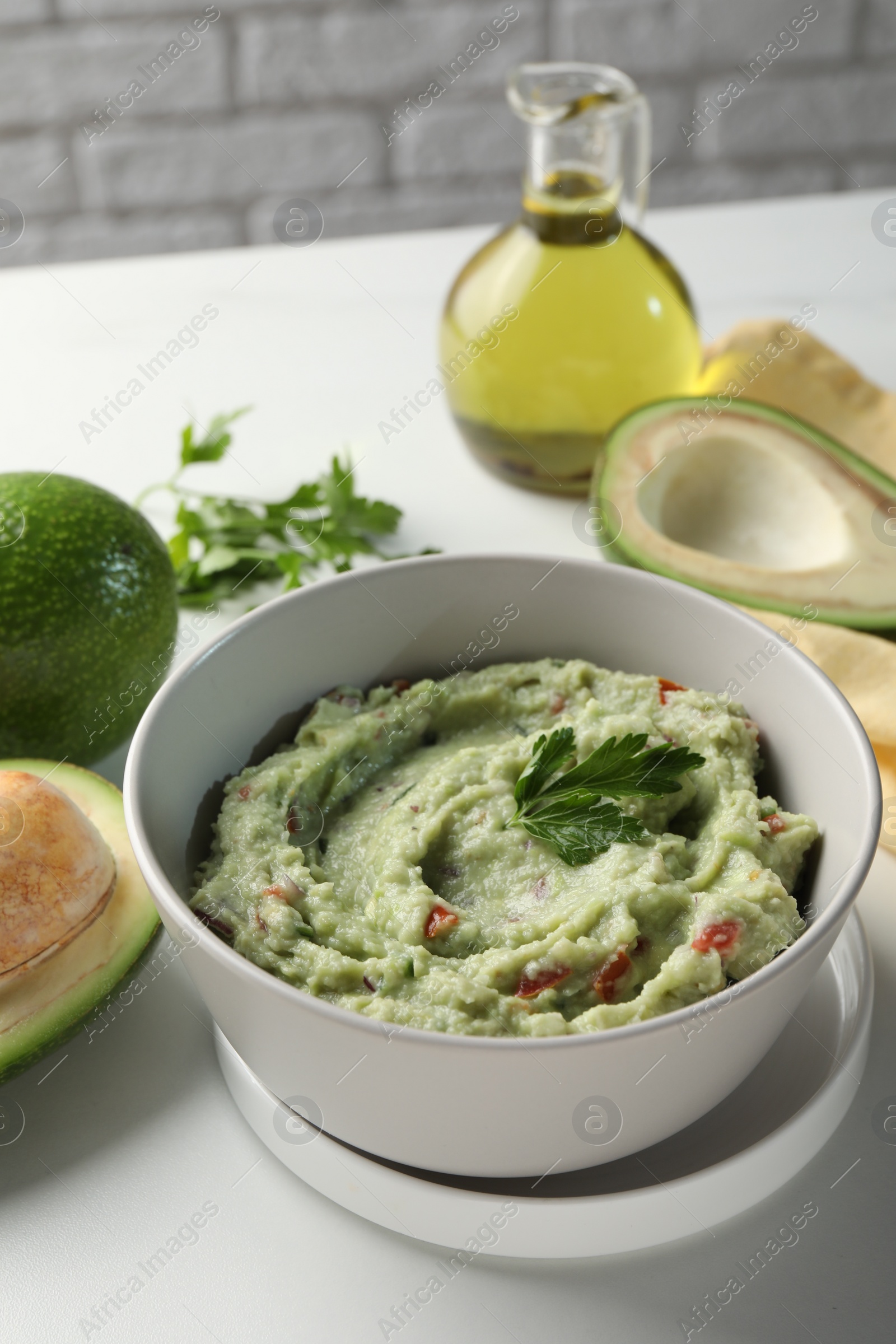 Photo of Delicious guacamole and ingredients on white table