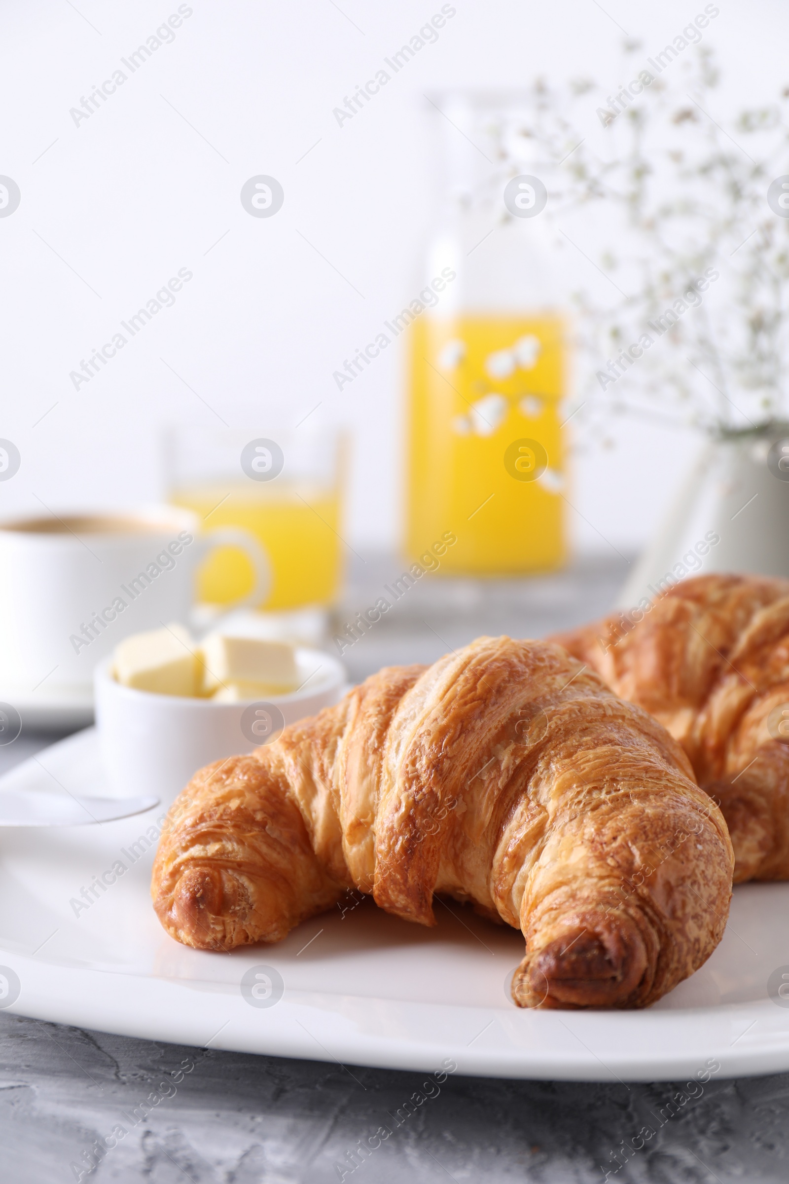 Photo of Tasty breakfast. Fresh croissants and butter on grey table, closeup