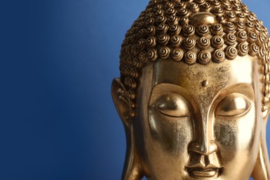 Photo of Beautiful golden Buddha sculpture on blue background, closeup. Space for text