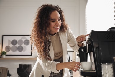Photo of African American woman preparing fresh aromatic coffee with modern machine in office