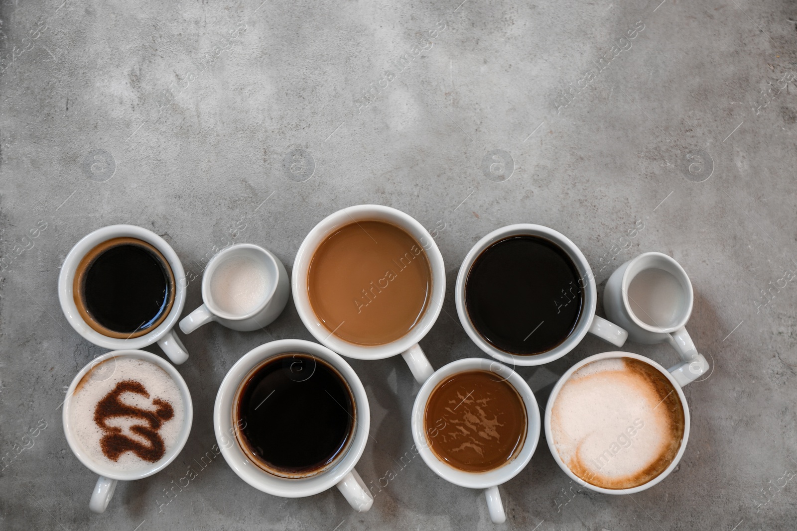 Photo of Cups of fresh aromatic coffee on grey background, top view