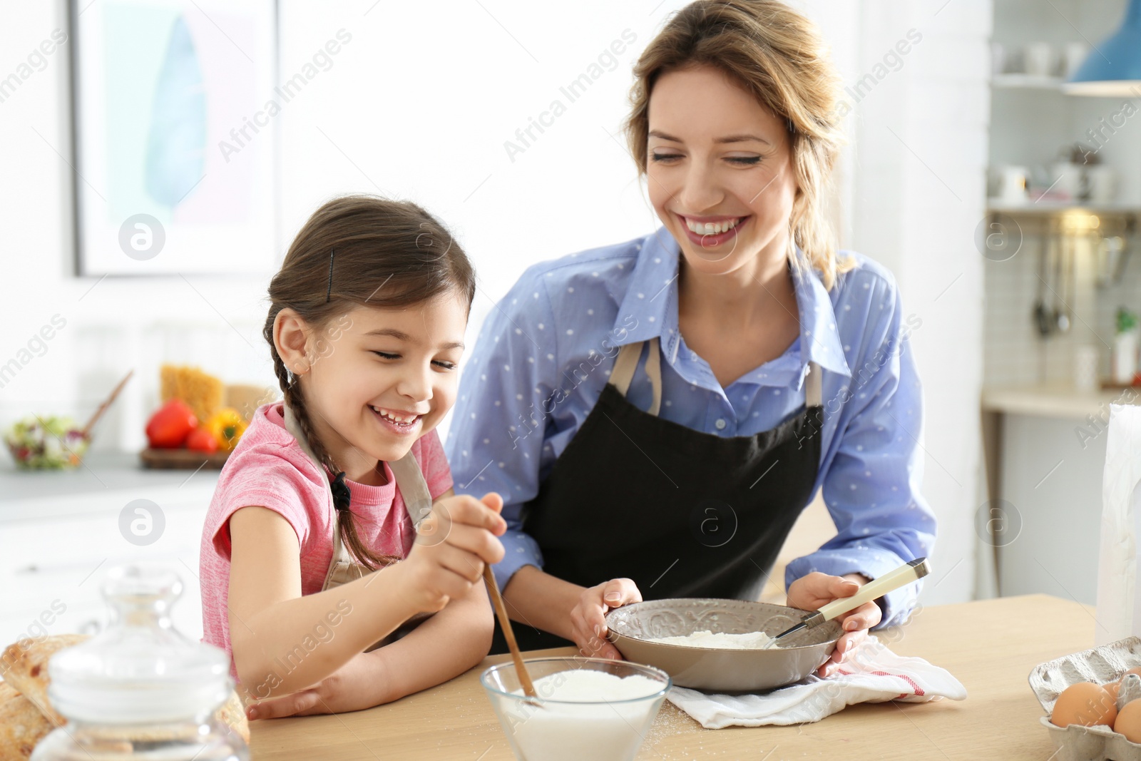 Photo of Young nanny with cute little girl cooking together in kitchen