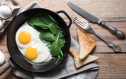 Photo of Delicious fried egg with spinach served on wooden table, flat lay