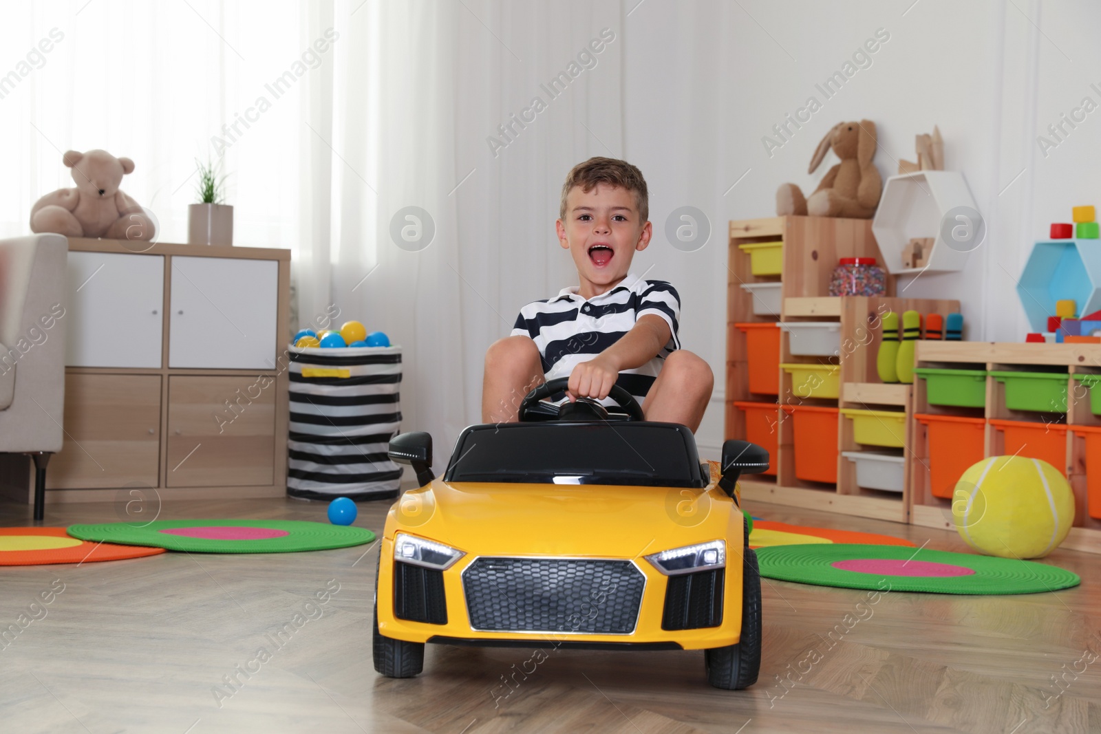 Photo of Emotional little boy driving big toy car at home