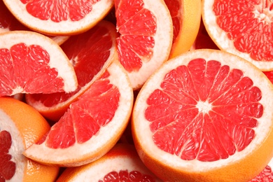 Photo of Many sliced fresh ripe grapefruits as background, closeup