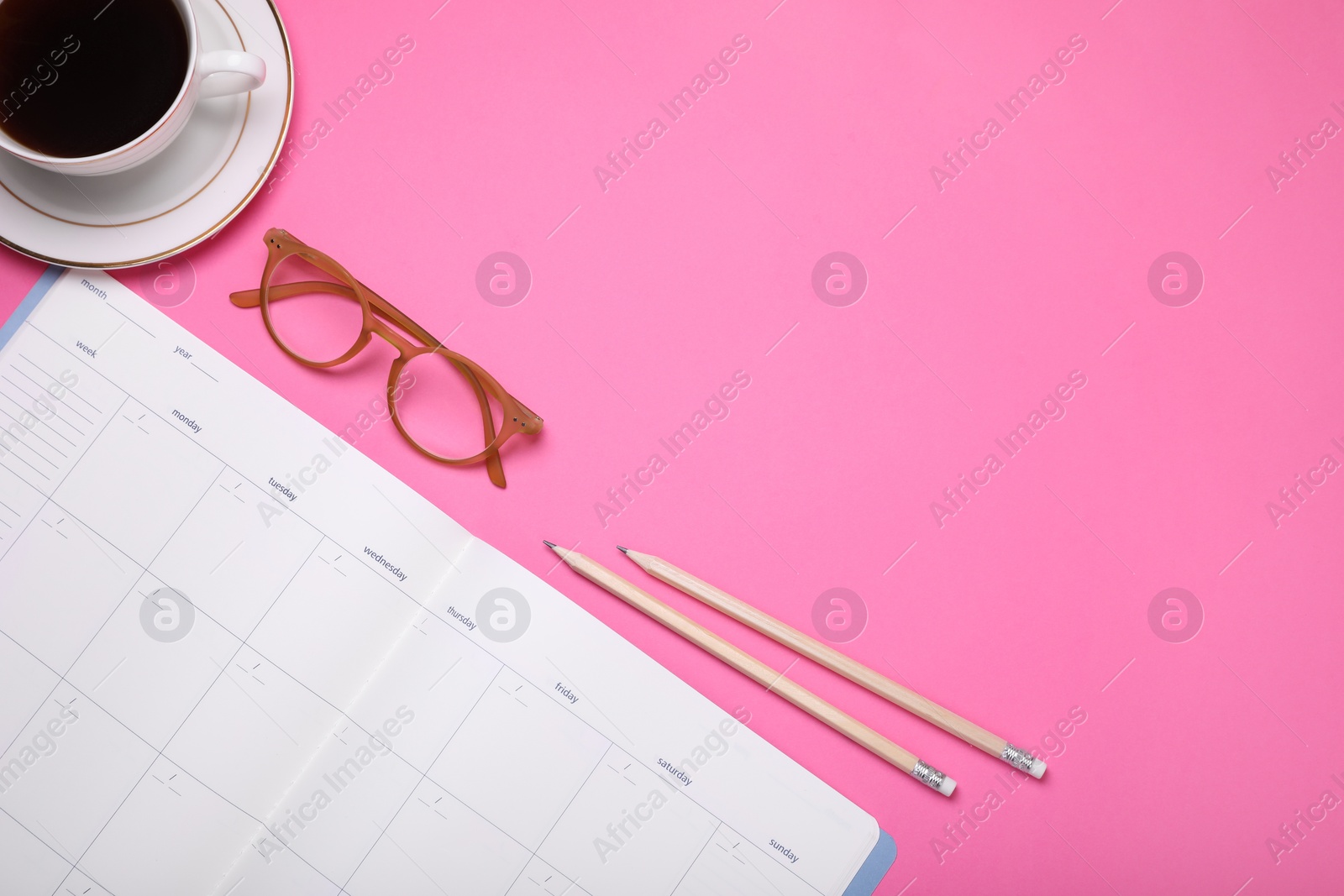 Photo of Open monthly planner, pencils, glasses and cup of coffee on pink background, flat lay. Space for text