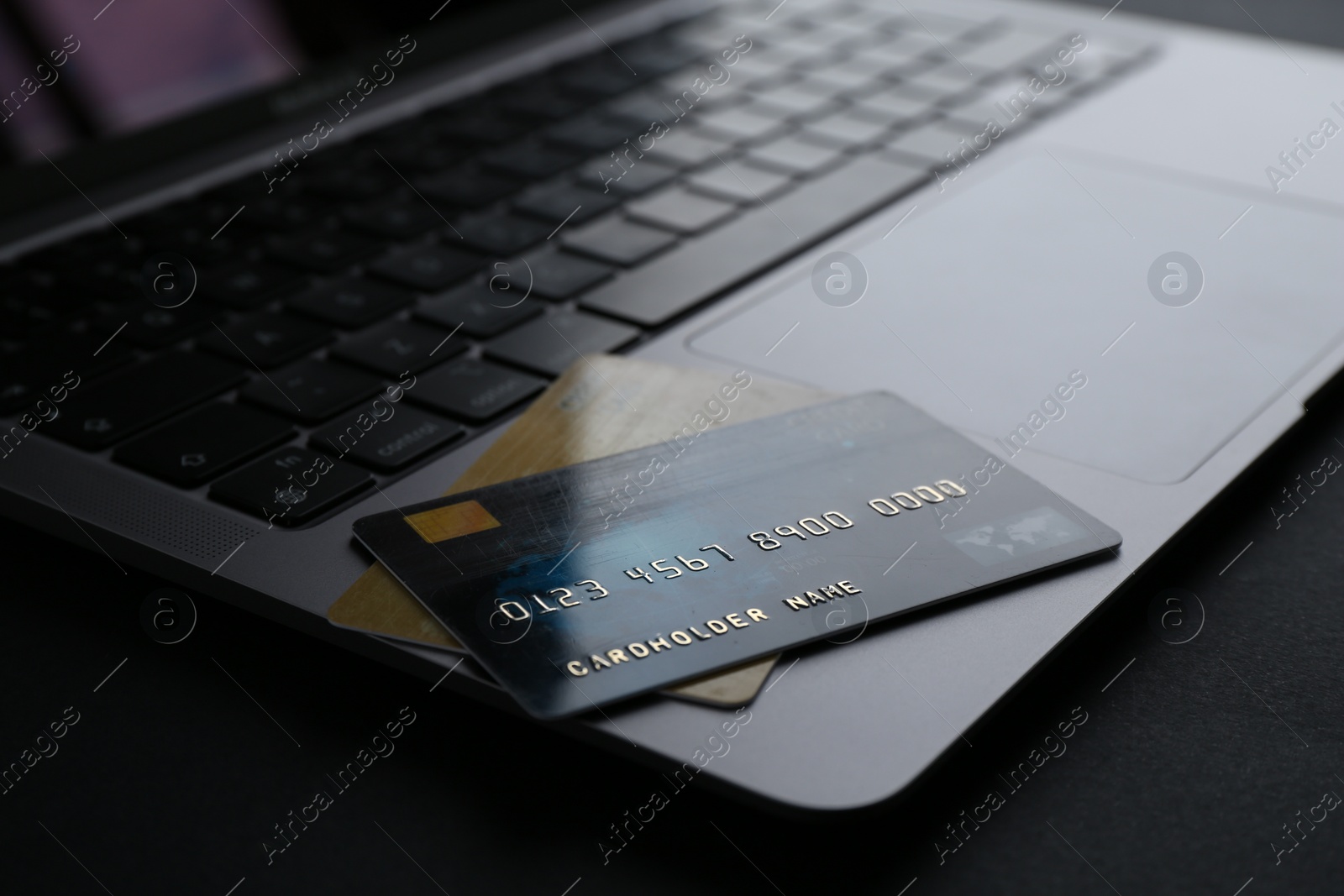 Photo of Laptop with credit cards on dark table, closeup