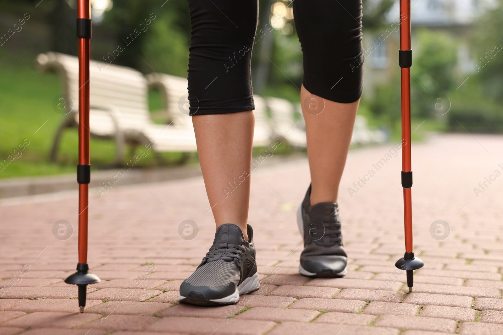 Photo of Young woman practicing Nordic walking with poles outdoors, closeup