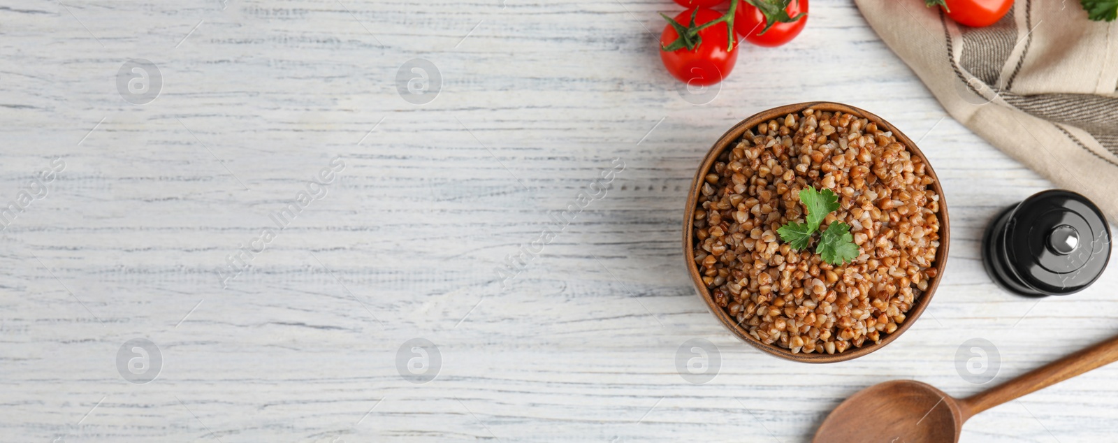 Image of Flat lay composition with bowl of buckwheat porridge served on white wooden table, space for text. Banner design
