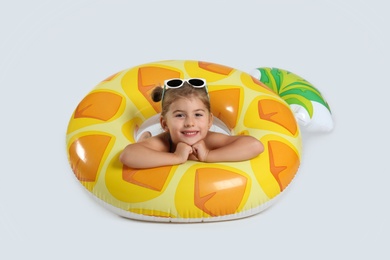 Cute little child in beachwear with bright inflatable ring on white background