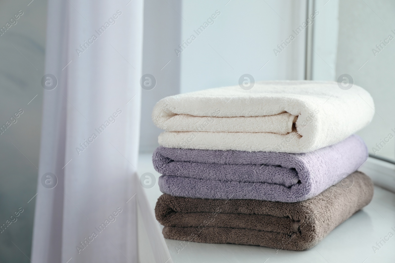 Photo of Stack of fresh towels on windowsill. Space for text