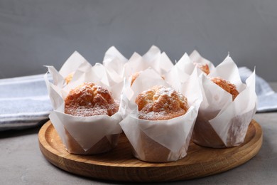 Photo of Delicious muffins with powdered sugar on grey table