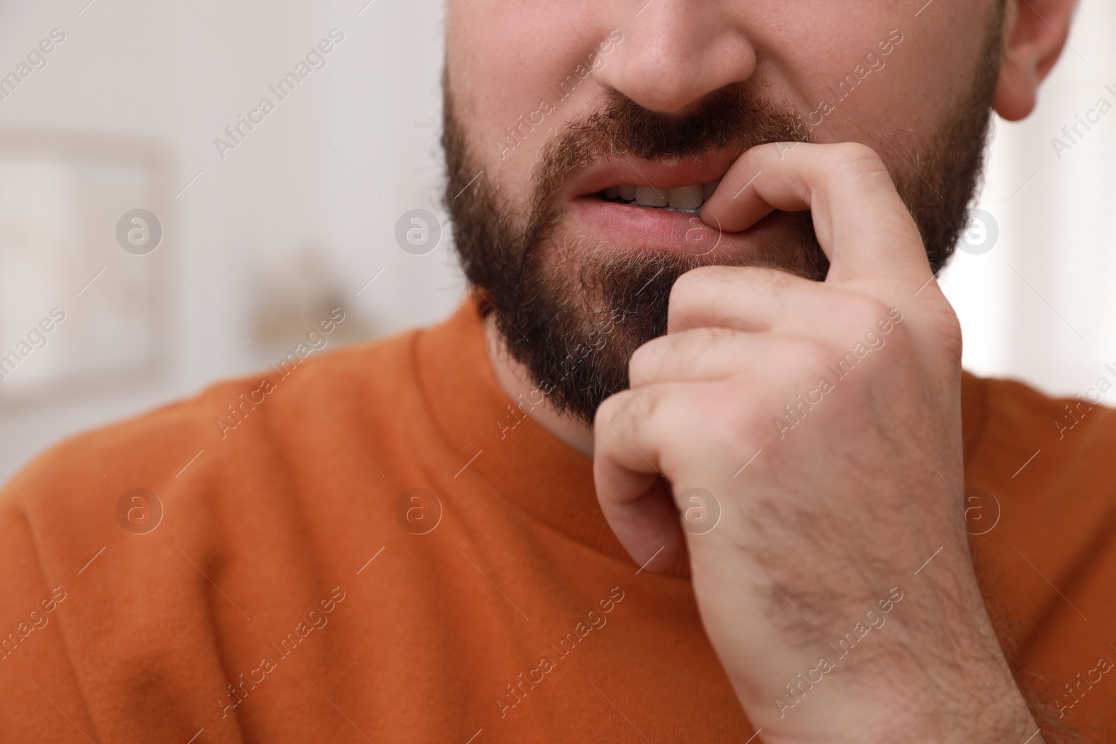 Photo of Man biting his nails on blurred background, closeup. Bad habit