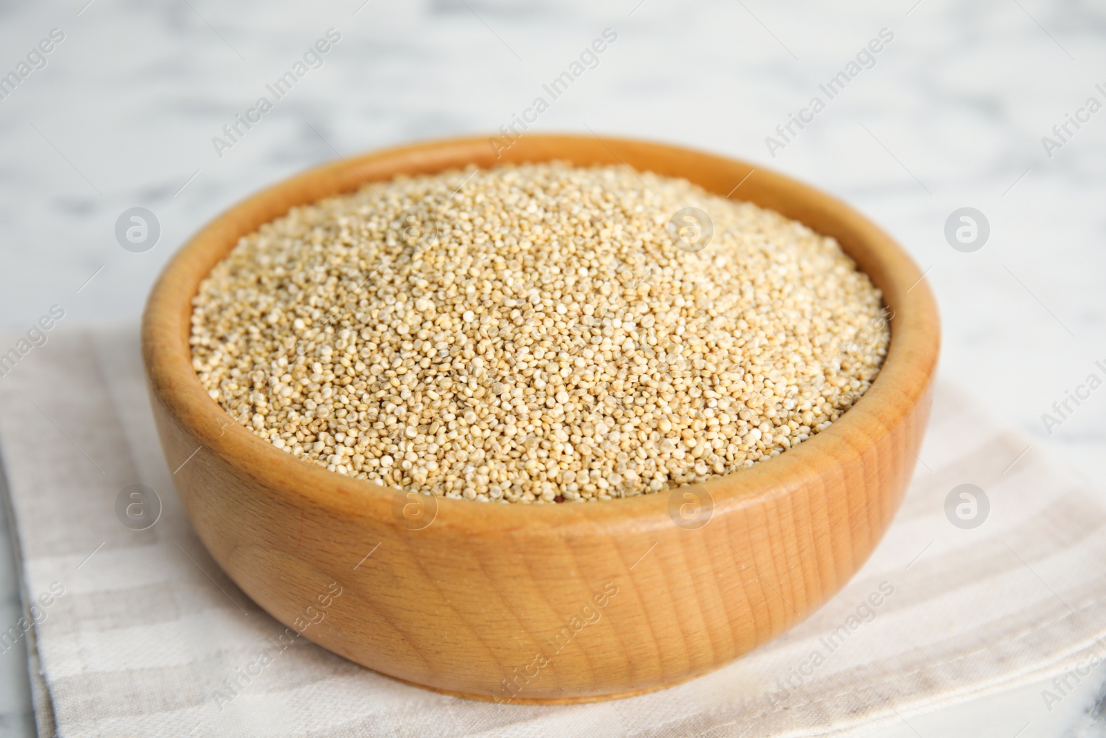 Photo of Wooden bowl with white quinoa on table, closeup