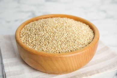 Wooden bowl with white quinoa on table, closeup