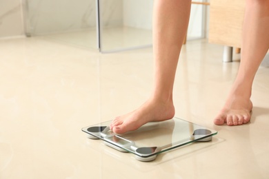 Photo of Woman stepping on floor scales in bathroom, space for text. Overweight problem