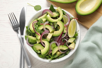 Photo of Delicious avocado salad with arugula on white wooden table, flat lay