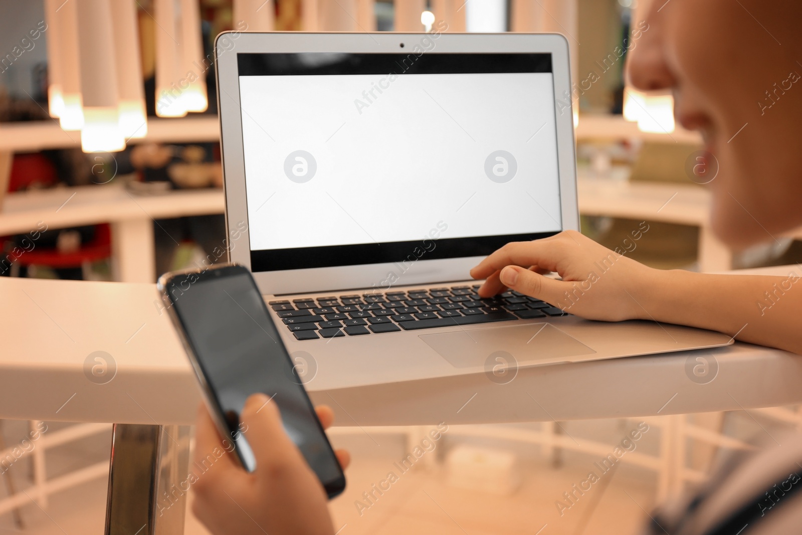 Photo of Blogger with laptop and mobile phone in cafe, closeup