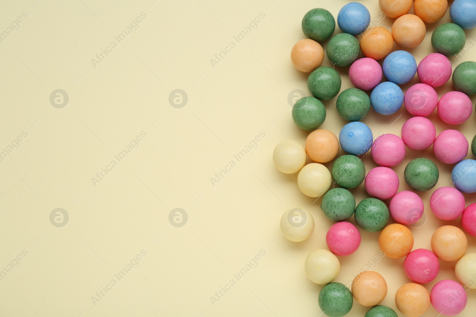 Photo of Many bright chewy gumballs on beige background, flat lay. Space for text