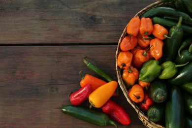 Photo of Many different fresh chilli peppers on wooden table, flat lay. Space for text