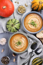 Photo of Flat lay composition with bowls of delicious pumpkin soup on gray wooden table