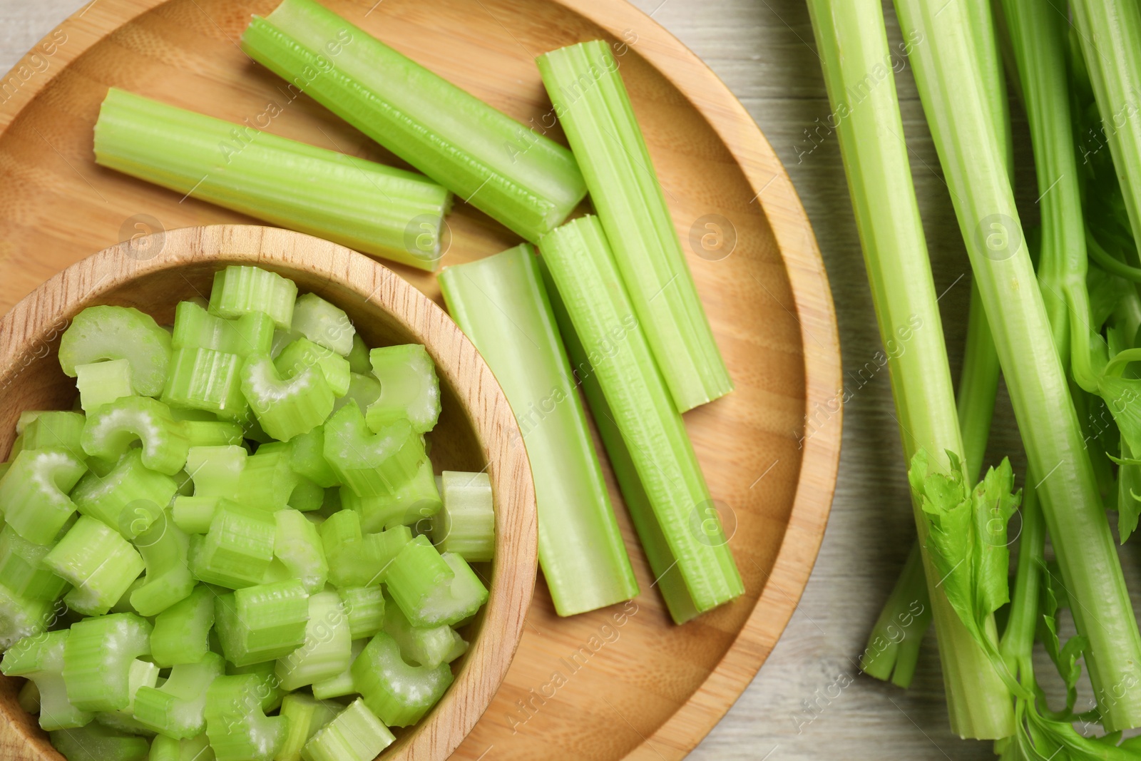 Photo of Many fresh cut celery stalks and leaves on wooden table, flat lay