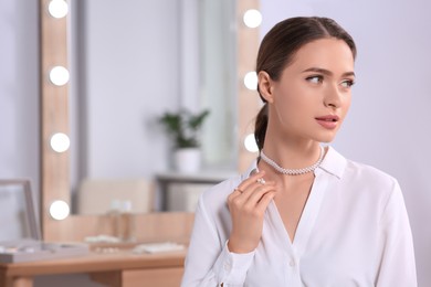 Photo of Young woman wearing elegant pearl jewelry indoors, space for text