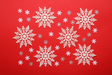 Photo of Beautiful decorative snowflakes on red background, flat lay