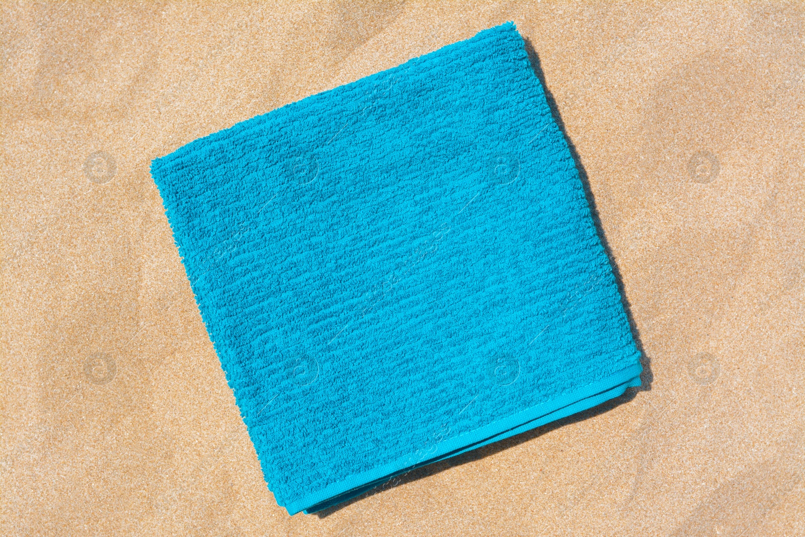 Photo of Soft blue beach towel on sand, top view