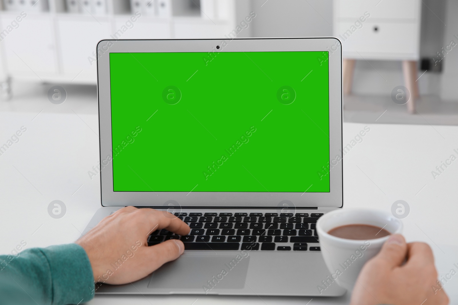 Image of Man using laptop at white desk, closeup. Device display with chroma key