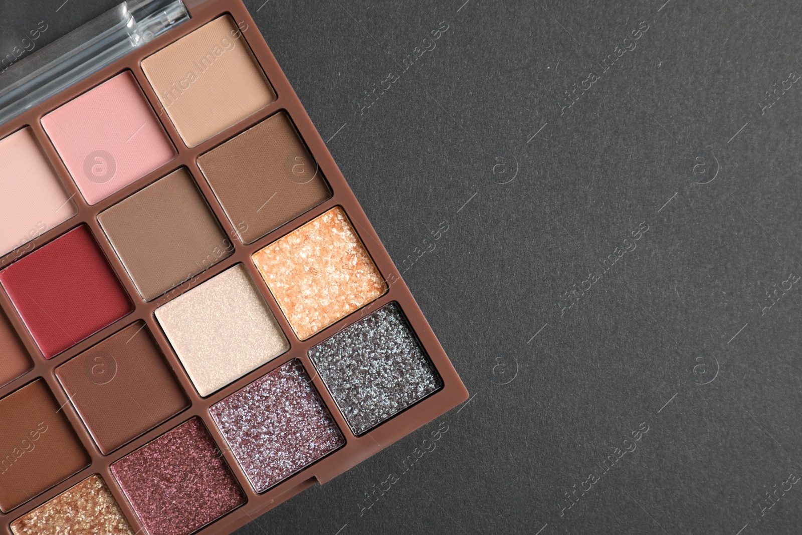 Photo of Colorful eyeshadow palette on dark background, top view. Space for text