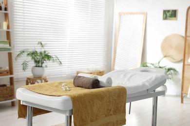 Massage table with towels and flowers in spa center