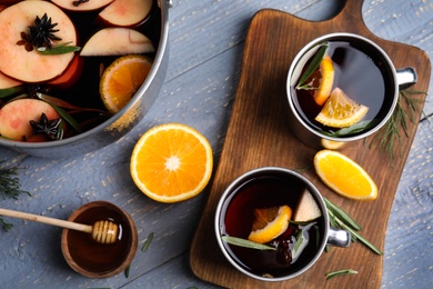 Photo of Tasty mulled wine with spices on grey wooden table, flat lay