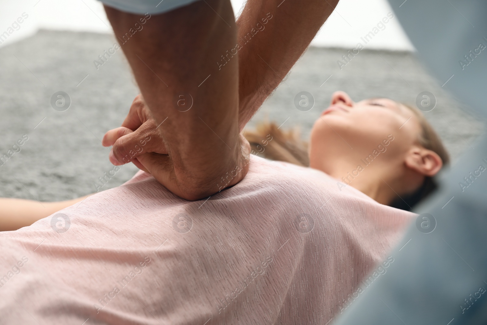 Photo of Man performing CPR on unconscious young woman indoors, closeup. First aid