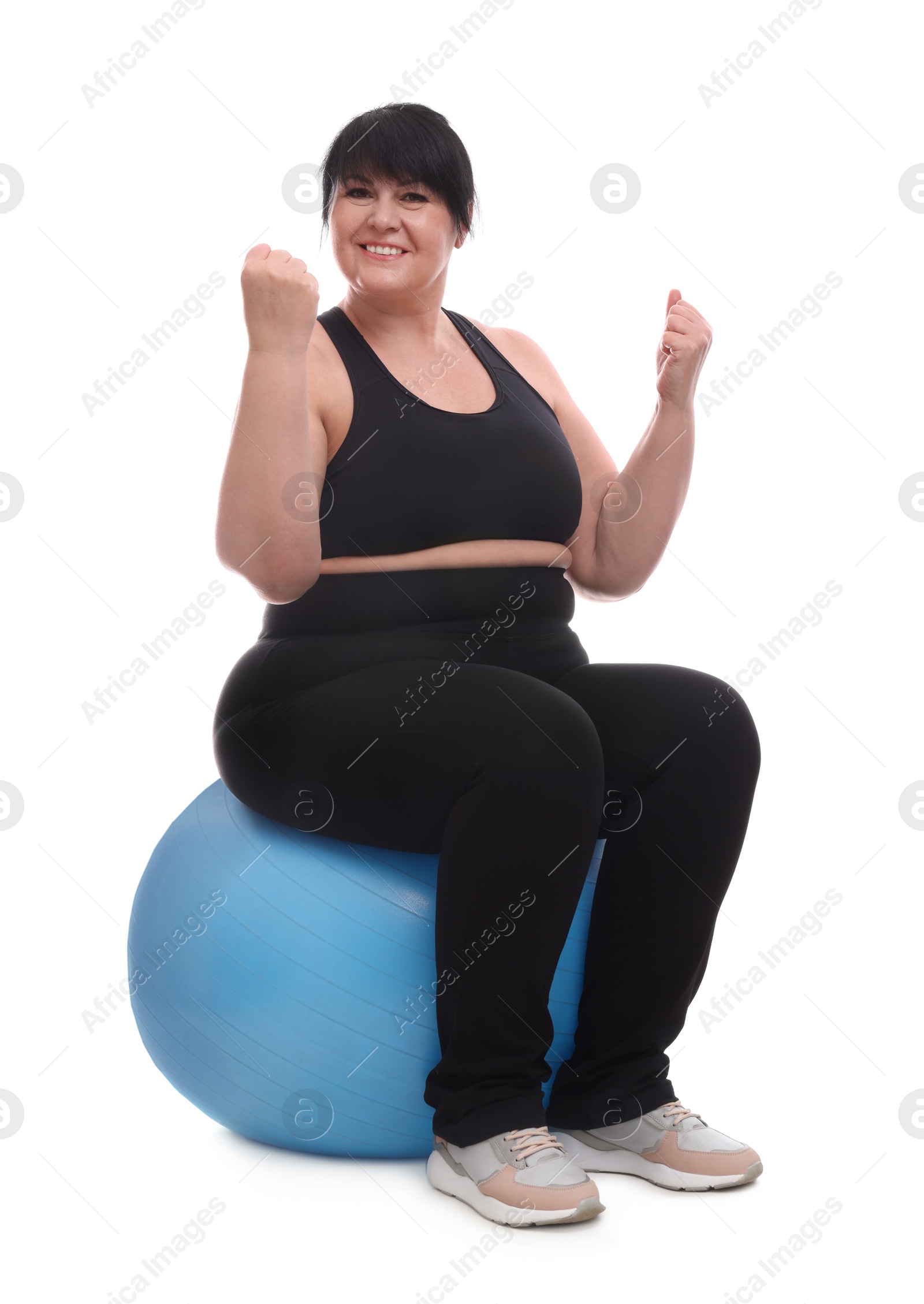 Photo of Happy overweight mature woman sitting on fitness ball against white background