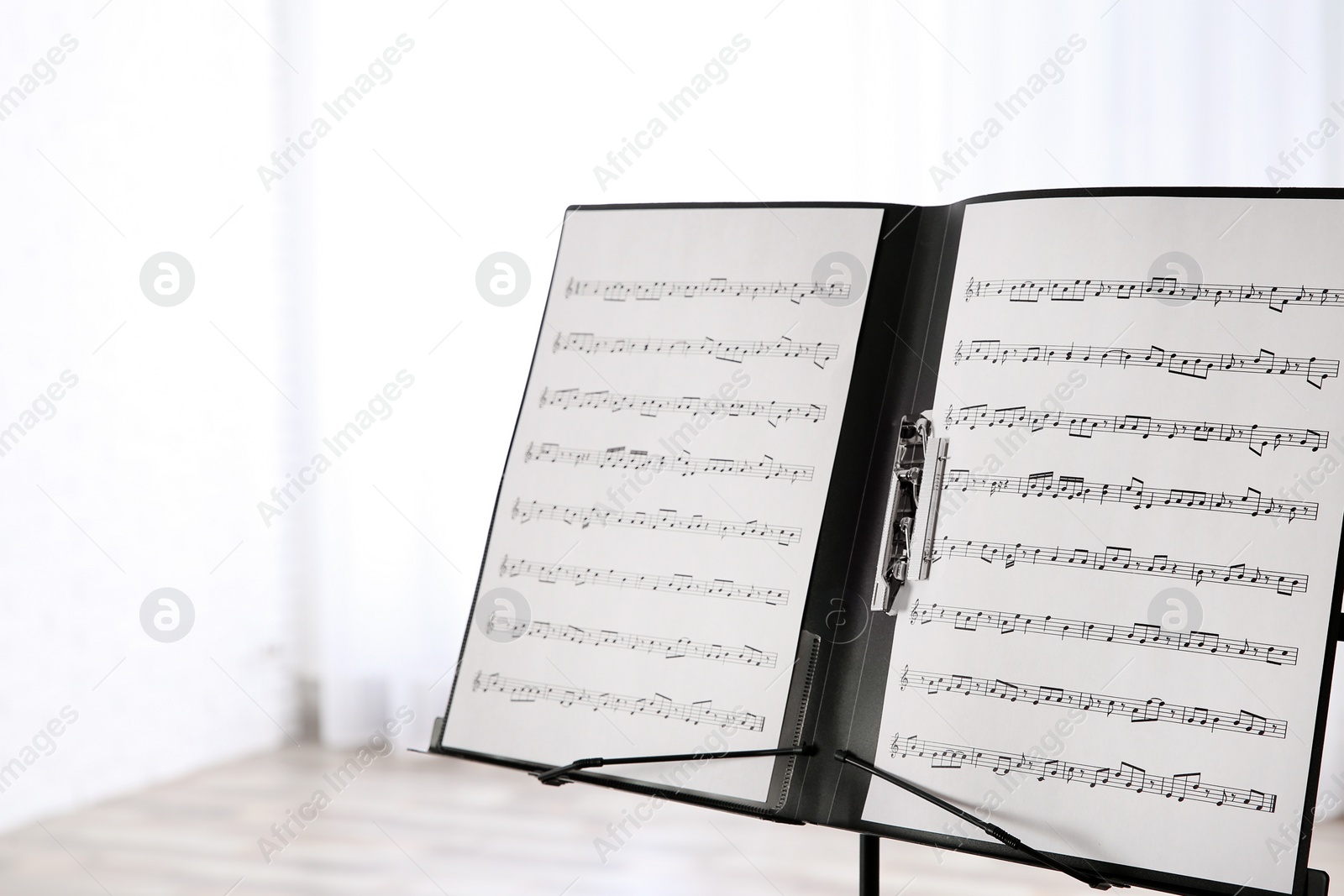 Photo of Note stand with music sheets indoors. Space for text