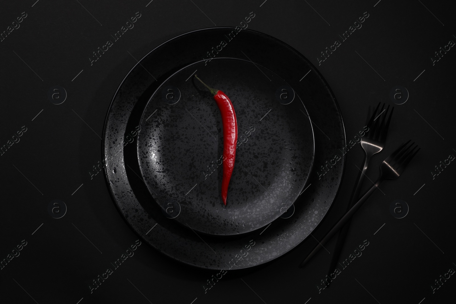 Photo of Stylish table setting. Plates, cutlery and red chilli pepper on black background, top view