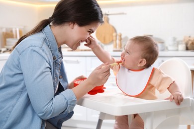 Photo of Mother feeding her cute little baby in kitchen