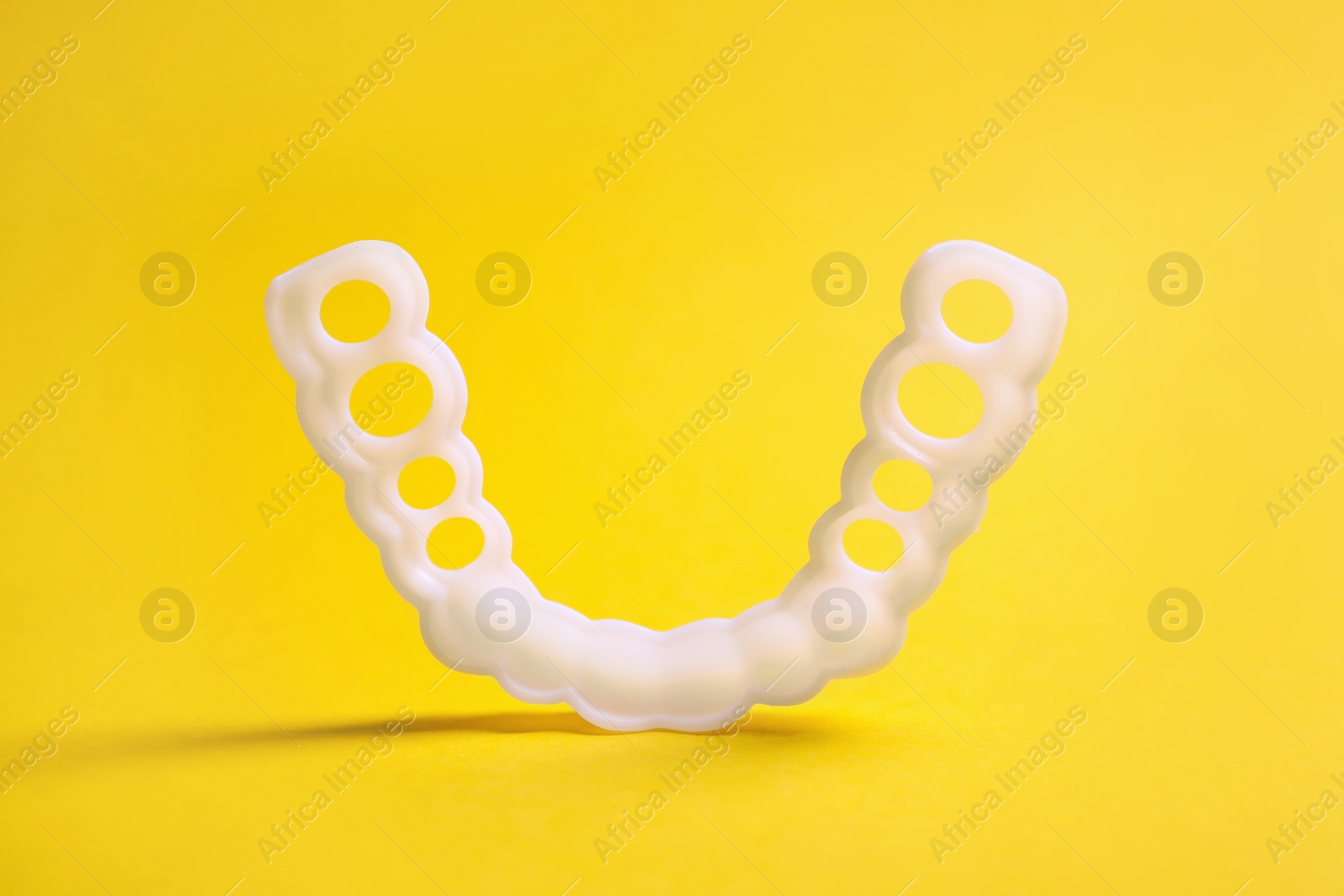 Photo of Dental mouth guard on yellow background, closeup. Bite correction