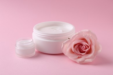 Moisturizing cream in open jars and rose flower on pink background. Body care product