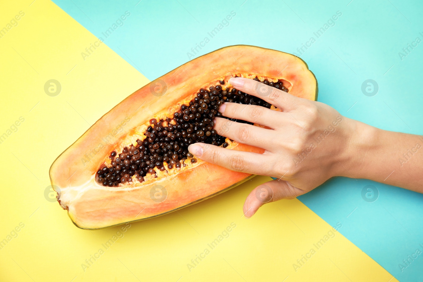 Photo of Young woman touching half of papaya on color background, top view. Sex concept