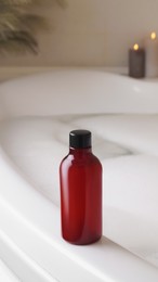 Photo of Red bottle of bubble bath on tub indoors