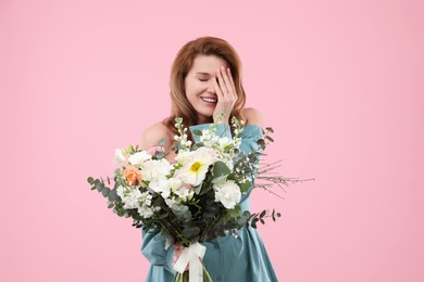 Beautiful woman with bouquet of flowers on pink background