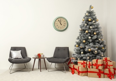 Photo of Stylish Christmas interior with decorated fir tree, table and chairs