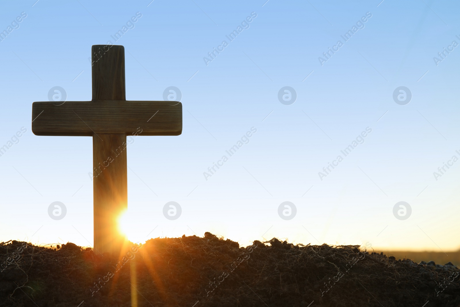 Photo of Wooden Christian cross outdoors at sunrise, space for text. Religion concept