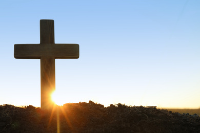 Photo of Wooden Christian cross outdoors at sunrise, space for text. Religion concept