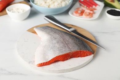 Photo of Fresh salmon and other ingredients for sushi on white marble table, closeup