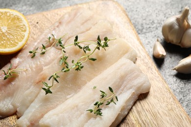 Photo of Raw cod fish, microgreens and lemon on grey textured table, closeup
