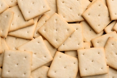 Many delicious crackers as background, top view