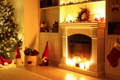 Photo of Cosy room with fireplace and burning candles in evening. Christmas atmosphere